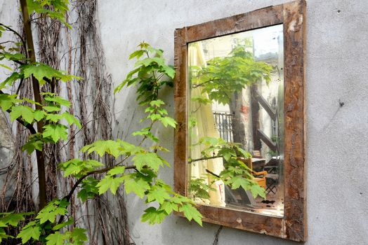 Old mirror hanging in Cracow on the wall of a brick walled house