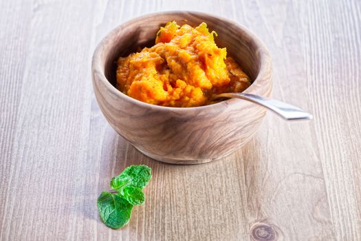 Pumpkin puree with greenery served on a wooden surface