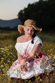 Vintage girl on the countryside with wicker hat on a flower field.