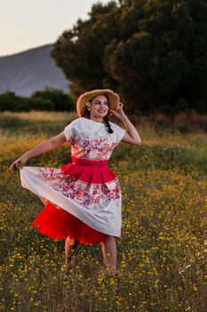 Vintage girl on the countryside with wicker hat on a flower field.