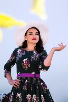 Vintage girl with beautiful floral dress with a white hat.