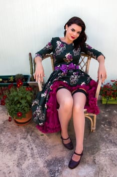 Vintage girl with floral dress posing on a wooden chair.