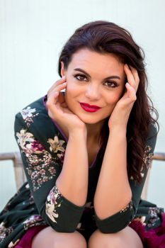 Vintage girl with floral dress posing on a wooden chair.