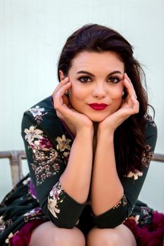 Vintage girl with floral dress posing on a wooden chair.