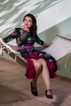 Vintage girl with floral dress relaxing on hammock.