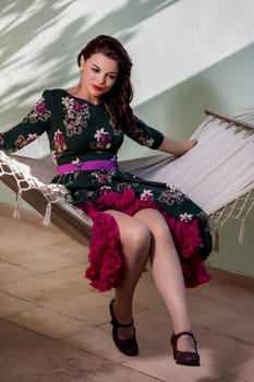 Vintage girl with floral dress relaxing on hammock.