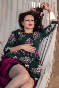 Vintage girl with floral dress relaxing on hammock.