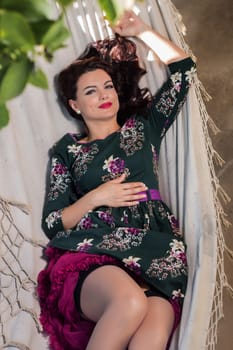 Vintage girl with floral dress relaxing on hammock.