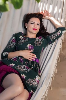 Vintage girl with floral dress relaxing on hammock.