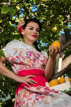 Vintage girl with floral dress climbing a lemon tree.