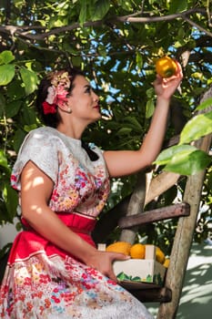 Vintage girl with floral dress climbing a lemon tree.