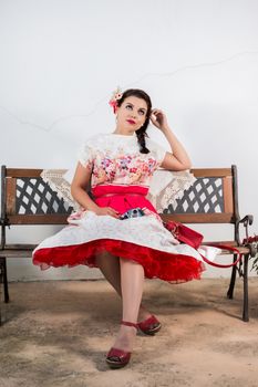 Vintage girl with floral dress relaxing on a park bench.