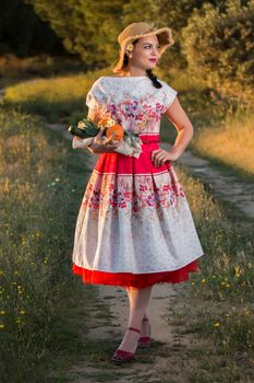 Vintage girl on the countryside with wicker hat gathering groceries.