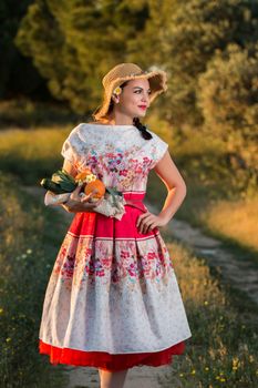 Vintage girl on the countryside with wicker hat gathering groceries.