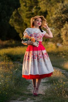 Vintage girl on the countryside with wicker hat gathering groceries.