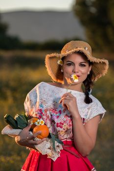 Vintage girl on the countryside with wicker hat gathering groceries.