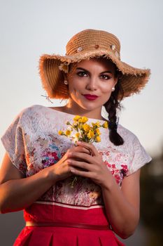 Vintage girl on the countryside with wicker hat with bouquet of flowers.