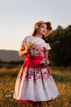 Vintage girl on the countryside with wicker hat with retro camera.