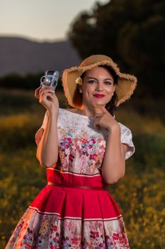 Vintage girl on the countryside with wicker hat with retro camera.