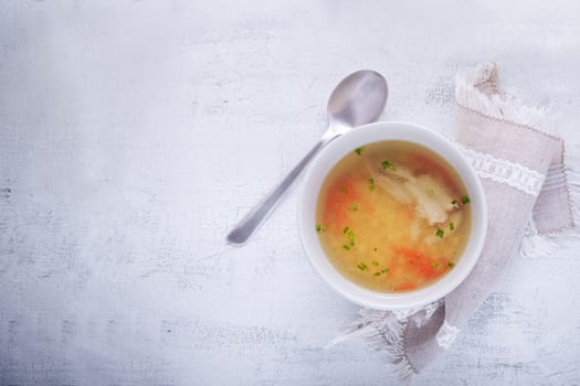 Homemade chicken soup with a spoon on a white napkin
