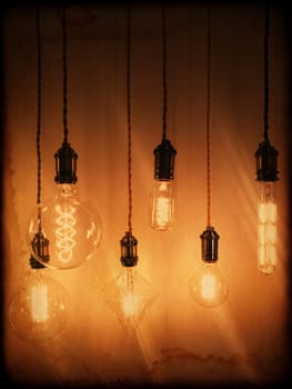 Illuminated light bulbs of different shapes on a vintage background.