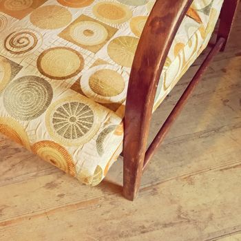 Detail of a vintage textile armchair on wooden floor. Retro style furniture.