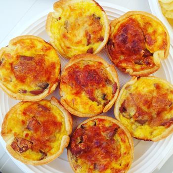 Several mini tasty quiches on a plate.