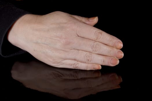 Female hand and its reflection on a black background