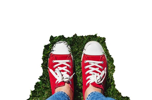 Legs in old red sneakers on green grass. View from above. The concept of youth, spring and freedom. Isolated on white background.