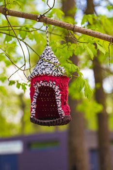 knitted from yarns birdhouse hanging in the park