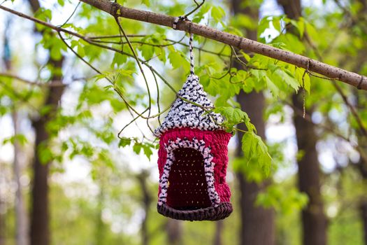 knitted from yarns birdhouse hanging in the park