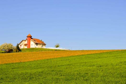 House with a turret over fields cultivated in the Meuse in France