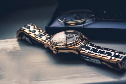 golden watch laying flat on a wooden board