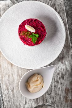 Salad with beet and herring on a wooden surface.