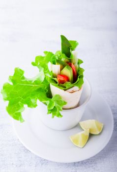 Vegetable wrap sandwiches with greenery on a white surface