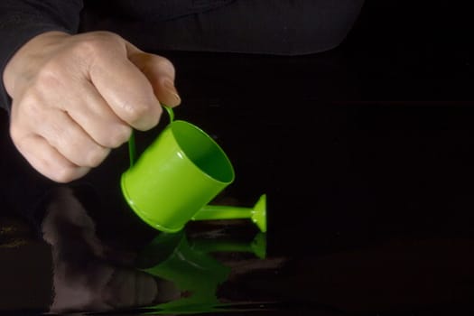 Female hand holding a watering can in front of a chalkboard