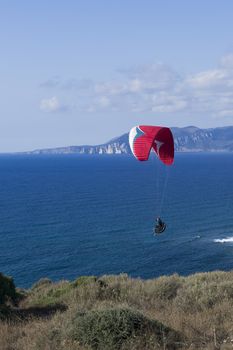 Colorful hang glider in sky over blue sea 