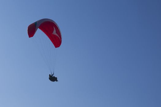 Colorful hang glider in sky over blue sea 
