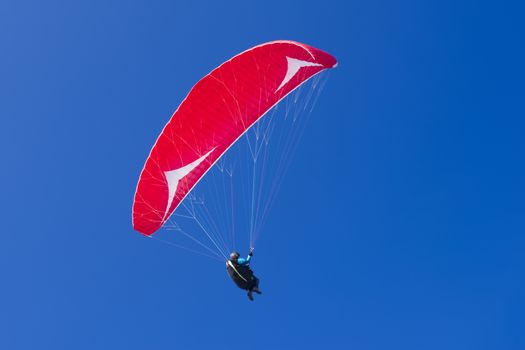 Colorful hang glider in sky over the mediterranean blue sea. Sardinia west coast. 