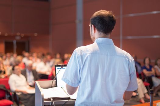Casualy dressed professor giving talk at scientific conference. Audience at the conference hall. Research experts and entrepreneurship event.
