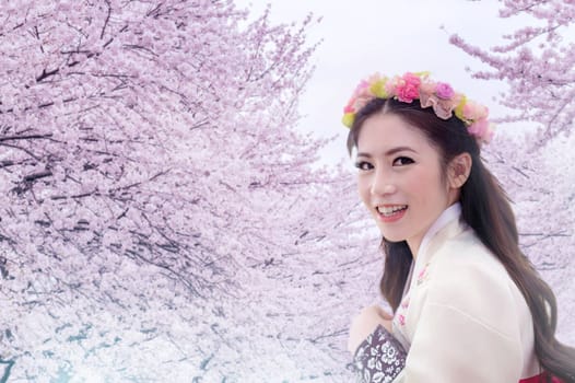 Asian woman wearing traditional korean hanbok with cherry blossom background.