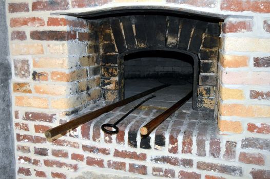 Old red brick-built baker's oven with a door in cast iron.