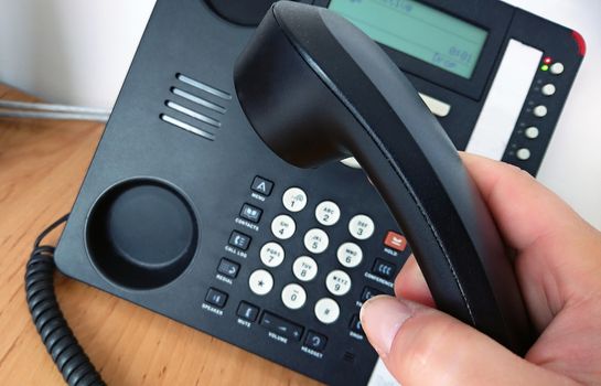 Close-up of picking telephone handset up for making a call.