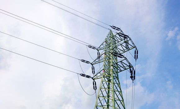 Low angle view of a power line pole with blue sky and clouds.