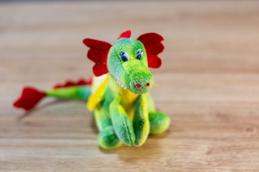 Knitted dragon isolated on wooden background.