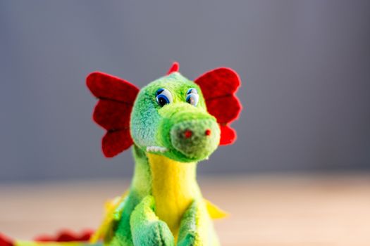 Knitted dragon isolated on wooden background.