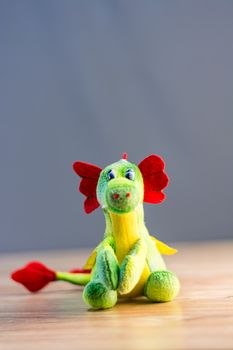 Knitted dragon isolated on wooden background.