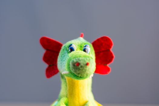 Knitted dragon isolated on wooden background.