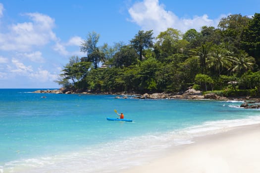 Tropical beach scenery at Andaman sea in Phuket, Thailand. Exotic sea view with people relaxing on vacation at tropical summer paradise beach of Phuket island with sunny sky and clouds on horizon
