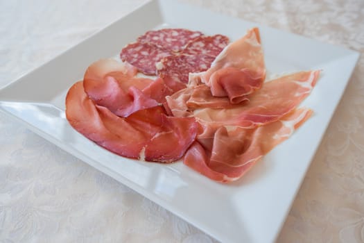 Mix of various Italian salami on white plate servided at restaurant,.